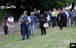 Police escort witnesses away from a mosque in central Christchurch, New Zealand, Friday, March 15, 2019.
