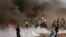 Protesters run to cover from teargas fired by Israeli troops, while others burn tires near fence of Gaza Strip border with Israel, during a protest east of Gaza City, Friday, Sept. 7, 2018. A teenager was killed and dozens of other Palestinians injured by