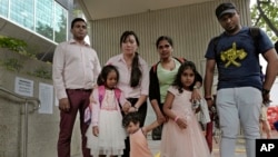 Asylum seekers, from left: Ajith Pushpa Kumara, Vanessa Mae Rodel and her daughter Keana, Nadeeka Dilrukshi Nonis and her son Dinath and daughter Sethmundi Kellapatha, and Supun Thilina Kellapatha, pose outside the building of Hong Kong's immigration department in Hong Kong, May 15, 2017. 