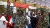 A Kenyan police officer gestures as stranded passengers wait for their delayed flights at JKIA airport after flights were grounded following workers’ protesting a planned deal between the government and a foreign investor, in Nairobi, Sept. 11, 2024. 