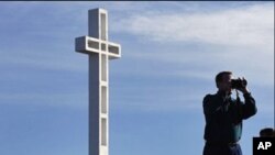 游人在有争议十字架战争纪念碑前摄影