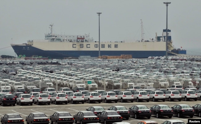 FILE - Newly-manufactured cars and a container ship are seen at Dayaowan port of Dalian, Liaoning province, June 10, 2012.