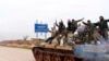  Syrian government soldiers flash victory signs, Feb. 12, 2020, as they patrol the highway that links the capital Damascus with the northern city of Aleppo, Syria. 