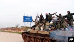  Syrian government soldiers flash victory signs, Feb. 12, 2020, as they patrol the highway that links the capital Damascus with the northern city of Aleppo, Syria. 