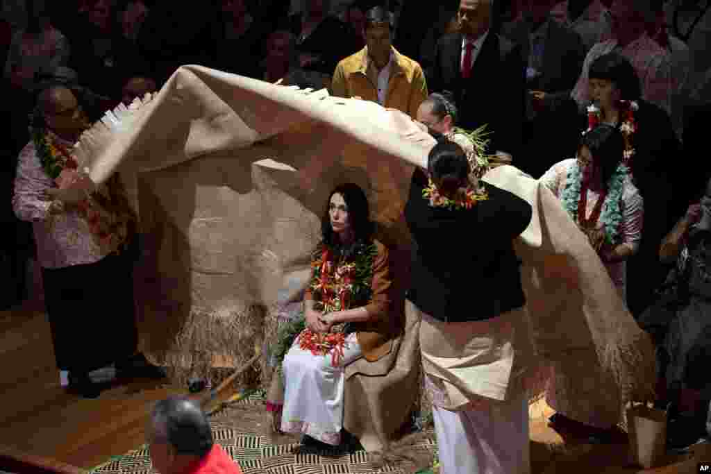 New Zealand Prime Minister Jacinda Ardern, center, is covered during a ceremony in Auckland, to formally apologize for a racially charged part of the nation&#39;s history known as the Dawn Raids.