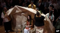 New Zealand Prime Minister Jacinda Ardern, center, is covered during a ceremony in Auckland, Aug. 1, 2021, to formally apologize for a racially charged part of the nation's history known as the Dawn Raids.