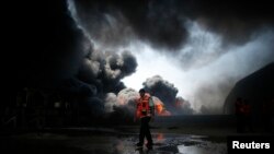 Un bombero participa en los intentos por apagar un incendio en la planta de electricidad de Gaza, alcanzada por los bombardeos irsraelíes de este martes.