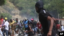 Un grupo de personas huye de los gases lacrimógenos disparados por la policía para dispersar a los manifestantes que exigían a la policía y al primer ministro medidas inmediatas contra las pandillas en Puerto Príncipe, Haití, el lunes 19 de agosto de 2024.