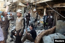 Civil defense members rest amid rubble of damaged buildings after an airstrike on the rebel-held Tariq al-Bab neighborhood of Aleppo, Syria, April 23, 2016.
