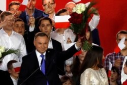 Polish President and presidential candidate of the Law and Justice (PiS) party Andrzej Duda holds up a bouquet after the announcement of the first exit poll results on the second round of the presidential election in Pultusk, Poland, July 12, 2020.