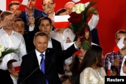 File - Polish President and presidential candidate of the Law and Justice (PiS) party Andrzej Duda holds up a bouquet after the announcement of the first exit poll results on the second round of the presidential election in Pultusk, July 12, 2020.