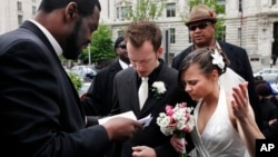 Bishop Harry R. Jackson Jr. of Beltsville, Md., left, prays with Jonathan Paul Ganucheau, 24, and Denise Buckbinder Ganucheau, 26, both of Dallas, Texas, before performing a religious wedding ceremony in Washington, May 5, 2009. 
