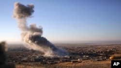 FILE - Smoke believed to be from an airstrike billows over the northern Iraqi town of Sinjar, Nov. 12, 2015. A man on an IS-released video denounced such strikes by "infidels."