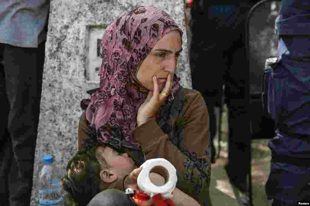 A woman sits with her child after migrants and refugees tried to open the border fence at a makeshift camp at the Greek-Macedonian border near the village of Idomeni, Greece, April 7, 2016.