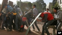 Egyptian protesters protect themselves behind makeshift shields during clashes with army troops near Tahrir Square in Cairo, Egypt, Dec. 18, 2011.