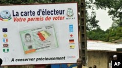 People walk in front of posters for the presidential elections and instructions on the voting card, Conakry, 25 Jun 2010