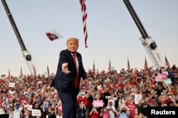 FILE - U.S. President Donald Trump throws a face mask from the stage during a campaign rally at Orlando Sanford International Airport in Florida, Oct. 12, 2020.