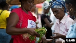 Kore Lavi participant buys food from program vendor. (Photo: USAID)