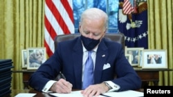 U.S. President Joe Biden signs executive orders in the Oval Office of the White House in Washington, after his inauguration as the 46th President of the United States, January 20, 2021.