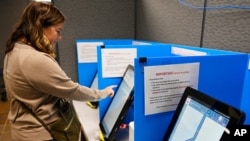 FILE - Courtney Parker votes on a new voting machine in Dallas, Georgia, Nov. 5, 2019,