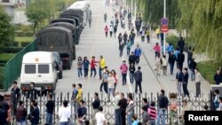 Trabajadores pasan cerca de un retén miliar a la entrada de la fábrica de Foxconn, en Taiyuan, provincia de Shanxi, el 24 de septiembre de 2012.