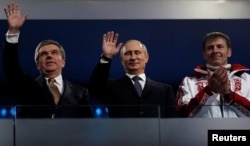 FILE - International Olympic Committee (IOC) President Thomas Bach of Germany and Russian President Vladimir Putin wave as gold medalist bobsleigh athlete Russia's Alexander Zubkov applauds during the closing ceremony for the 2014 Sochi Winter Olympics, Feb. 23, 2014.
