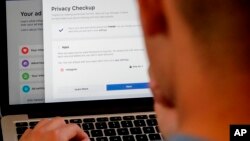 FILE - A man poses for a photo in front of a computer showing Facebook ad preferences in San Francisco, California, March 26, 2018.