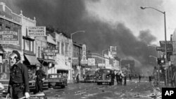 In this July 24, 1967, file photo, police check buildings along a section of 12th Street, about three miles from downtown Detroit, following racial riots which broke out in the city.