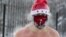 A member of the ice swimming club, wearing christmas face mask and hat, prepares to go swimming into the icy water as the temperature dropped down to minus 34 degrees celsius, in the Siberian city of Novosibirsk, on December 26, 2020.