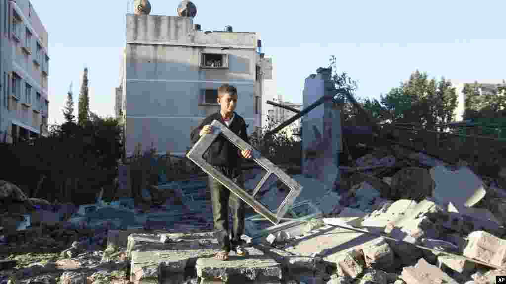 A Palestinian boy holds a window pane taken from a damaged house hit in an Israeli strike, in Gaza City, November 15, 2012.s