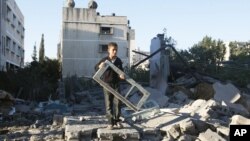 A Palestinian boy holds a window pane taken from a damaged house hit in an Israeli strike, in Gaza City, November 15, 2012.s