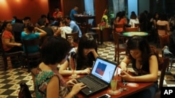 Three young Vietnamese girls use a laptop and smart phones to go online at a cafe in Ha Noi, Viet Nam Wednesday, May 14, 2013. (AP Photo/Na Son Nguyen).