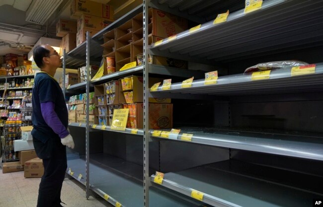 Un trabajador chequea estantes vacíos de arroz en un supermercado en Hong Kong, el jueves, 6 de febrero de 2020.