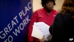 FILE - Jimmetta Smith of Lithonia, Ga., right, holds her resume while talking with Rhonda Knight, a senior recruiter for Delta airlines, at a job fair in Marietta, Ga., Nov. 14, 2013. 