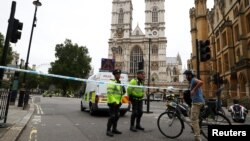 Para petugas kepolisian di daerah yang dibatasi dengan garis polisi setelah sebuah mobil menabrak di luar Gedung Parlemen di Westminster, Inggris, 14 Agustus 2018.