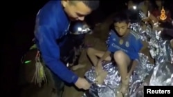 Dečaci fudbalskog tima za mlađe od 16 godina, zarobljeni unutar Tam Luang pećine, primaju pomoć od bolničara u Čiang Raiu na ovoj fotografiji napravljenoj od video-snimka mornaričkih foka, snimljenog 3. jula 2018.