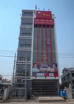 Seorang polisi menjaga di luar pintu tertutup kantor partai Liga Nasional untuk Demokrasi yang dihiasi dengan foto Aung San Suu Kyi (kanan) dan pelindung partai Tin Oo di Mandalay, Myanmar, Rabu, 3 Februari 2021.