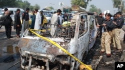 Pakistani police officers look at a damaged vehicle following blast in Peshawar, Pakistan, Oct. 2, 2014.