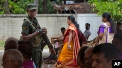 A soldier stands guard amid Catholics attending Mass outside St. Joseph's church in Thannamunai, Sri Lanka, April 30, 2019. 