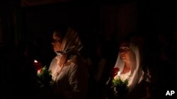 FILE —Christian orthodox women hold candles and flowers as they walk in a procession to bring an icon of the Virgin Mary to the tomb where it is believed she is buried, along the streets of the Old City of Jerusalem, August 25, 2023.