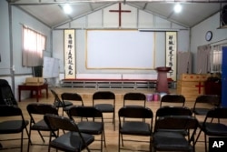 FILE - Calligraphy reading, "All nations belong to the Lord arising to shine," at left, and "Jesus' salvation spreads to the whole world," at right, are displayed in a house church shut down by authorities near Nanyang, China, June 4, 2018.