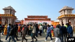 FILE - People walk along the entrance gate decorated by flowers in Ayodhya on January 21, 2024.