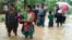 Nepalese villagers carry their belongings while wading through a flooded street to move to safer ground, at Bardia, in western Nepal, Aug. 15, 2014.