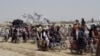 FILE - Supporters of the Taliban carry their signature white flags after the Taliban said they seized the Afghan border town of Spin Boldaka across from the town of Chaman, Pakistan, July 14, 2021.