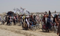 Supporters of the Taliban carry Islamic flags after the Taliban said they seized the Afghan border town of Spin Boldaka across from the town of Chaman, Pakistan, July 14, 2021.