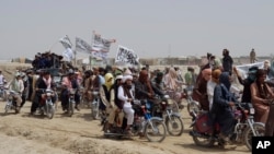 FILE - Supporters of the Taliban carry their signature white flags after the Taliban said they seized the Afghan border town of Spin Boldaka across from the town of Chaman, Pakistan, July 14, 2021.