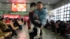 A woman and a youngster wait to board their train at the Beijing West Railway Station as families head home ahead of the Lunar New Year, Jan. 24, 2025.