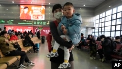 A woman and a youngster wait to board their train at the Beijing West Railway Station as families head home ahead of the Lunar New Year, Jan. 24, 2025.