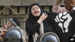 A protester in Egypt, behind a cordon of security officers, calls for an end to police brutality, Cairo, 13 Apr 2010