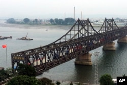 FILE - Trucks cross the friendship bridge connecting China and North Korea in the Chinese border town of Dandong, opposite side of the North Korean town of Sinuiju, Sept. 4, 2017. For Chinese traders, United Nations sanctions on North Korea are a disaster.